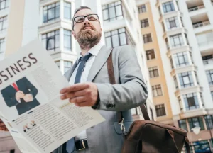NY Hard Money Loans for Rental Properties: What Investors Need to Know 2 A man holding a newspaper with the word "Business" prominently displayed on the front page.