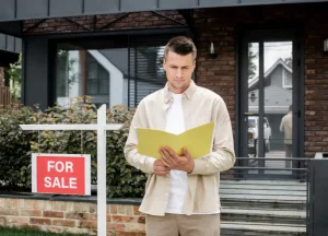 Man standing in front of a 'For Sale' house