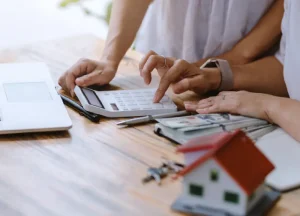 5 Common DSCR Loan Myths That Stop Investors from Growing 2 Person using a calculator to analyze rental property income and expenses for DSCR loan qualification.
