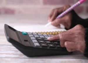 How to Calculate Profit Margins on a Fix and Flip Loan Project 3 Person calculating renovation costs using a calculator and paperwork for a fix and flip project.