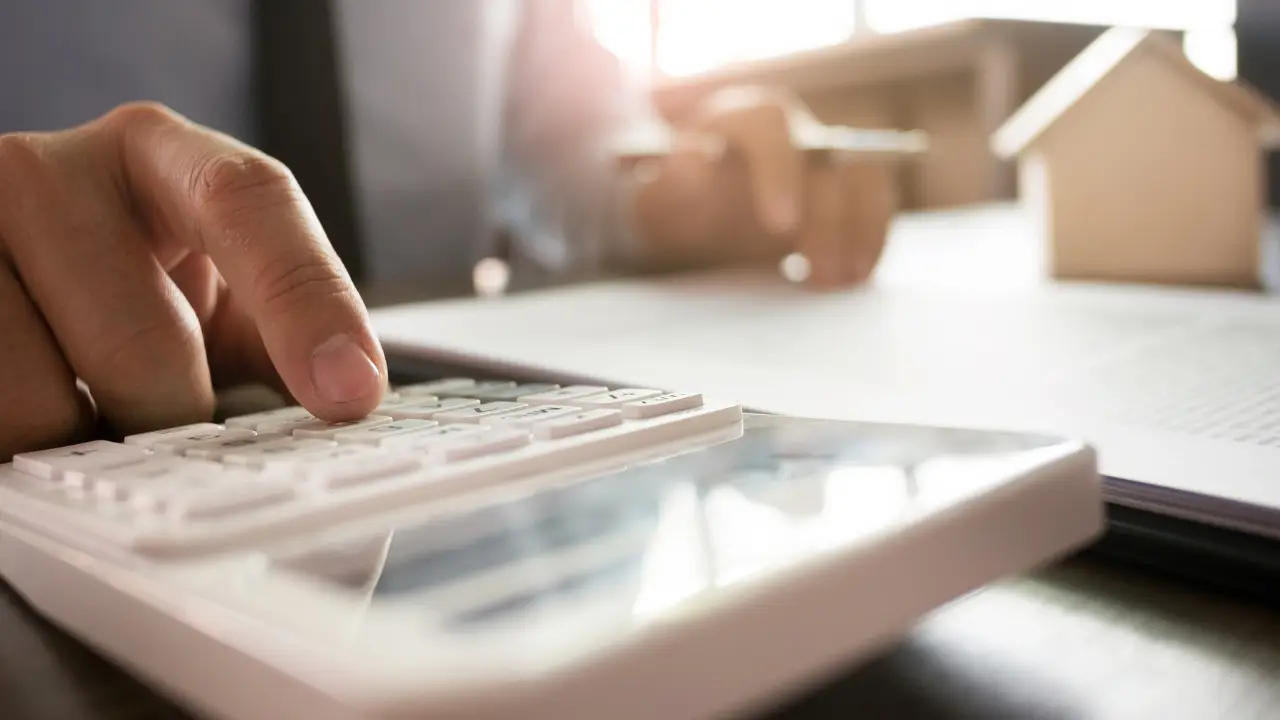 Person using a calculator to analyze short term rental income and expenses for DSCR loan qualification.