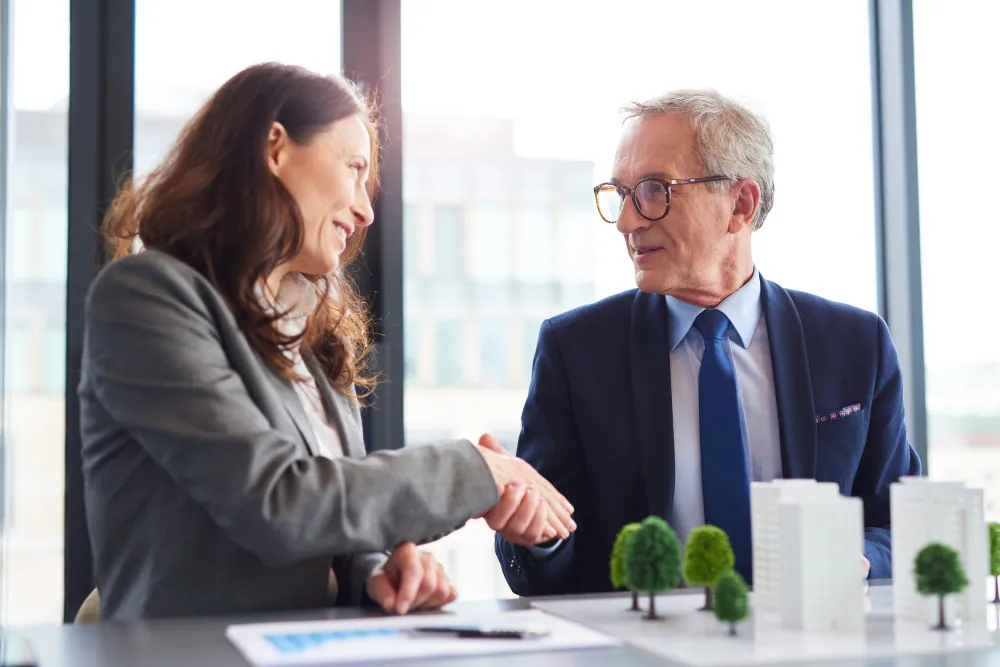 Real estate investor and direct hard money lender shaking hands over property project plans